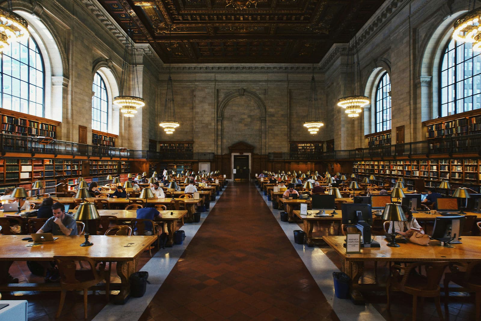 Library-style hall with classic tables full of books — symbol of an academic environment.