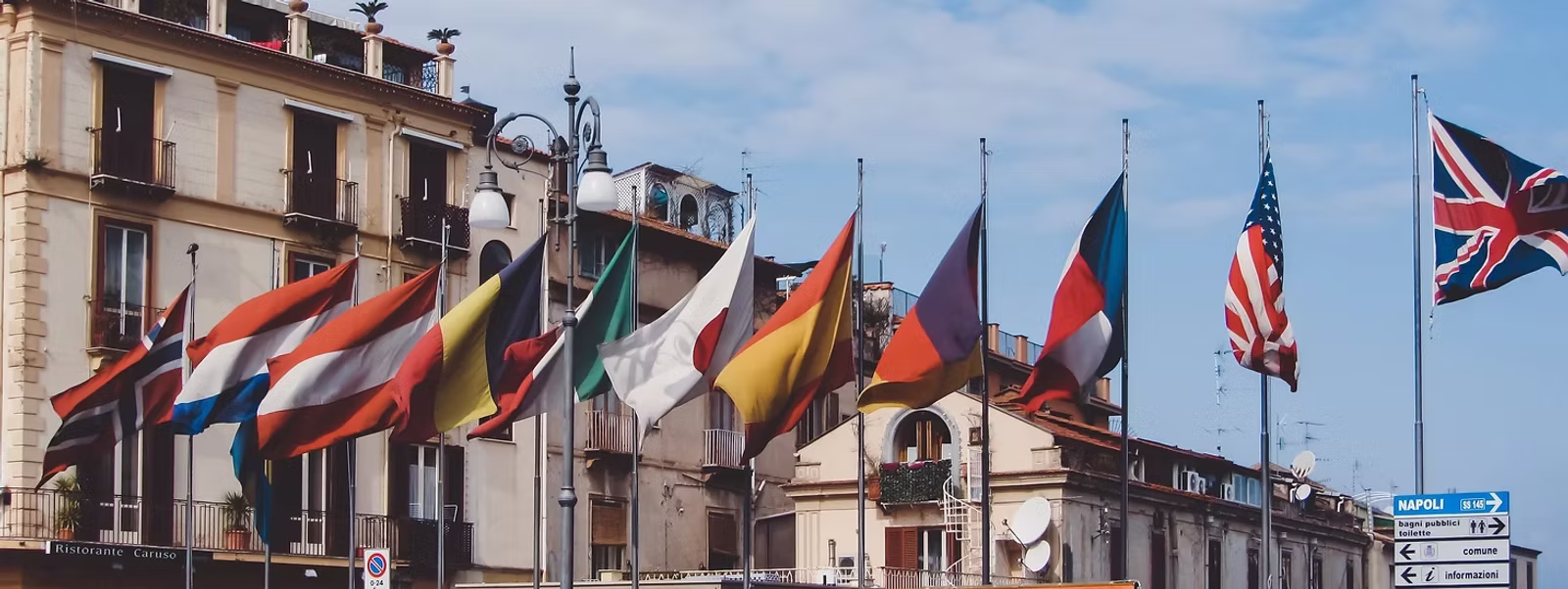 International flags lined up outside a classical European façade.